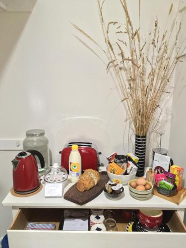 uma prateleira com alimentos de pequeno-almoço e um bule de chá e flores em A Suite Spot in the Hills em Mount Barker