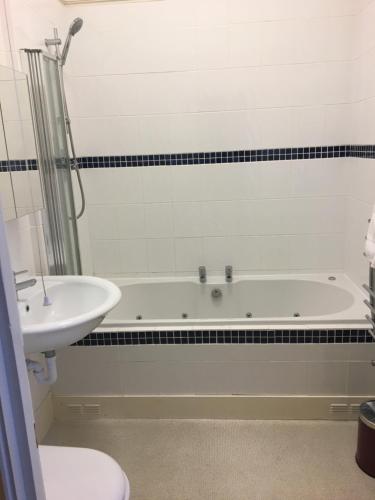 a bathroom with a bath tub and a sink at The Grosvenor in Clacton-on-Sea