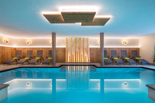una piscina de hotel con sillas y techo en Hotel Falken, en Falzes