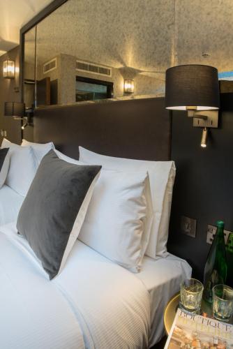 a bed with white pillows and a table with a lamp at Camden Enterprise Hotel in London