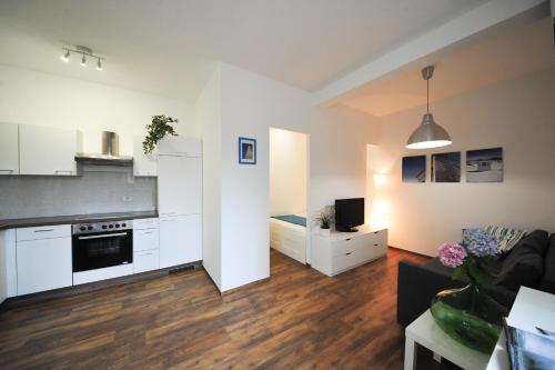 una cucina e un soggiorno con armadi bianchi e divano di Apartma Prešern a Izola