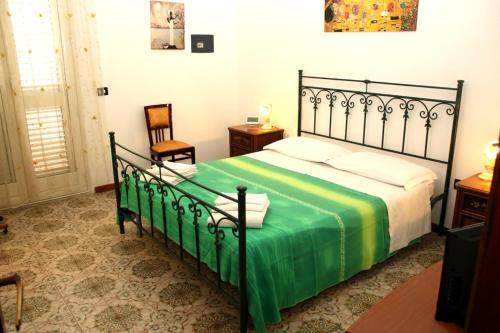 ein Schlafzimmer mit einem Bett mit einer grünen Decke und einem Stuhl in der Unterkunft B&B L' Aranceto in San Donaci