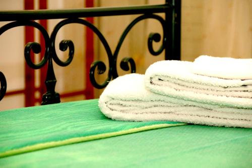 drei Handtücher auf einem grünen Bett gestapelt in der Unterkunft B&B L' Aranceto in San Donaci