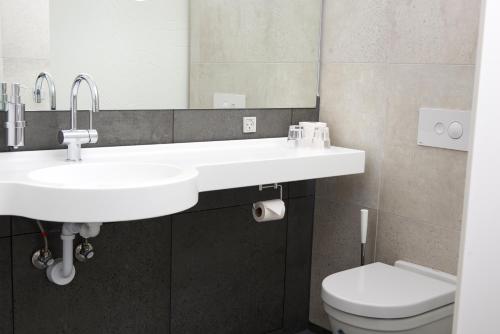 a bathroom with two sinks and a toilet at Fuglsangcentret Hotel in Fredericia