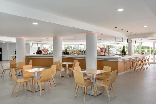 a restaurant with tables and chairs and a bar at Hotel Vibra Mare Nostrum in Playa d'en Bossa