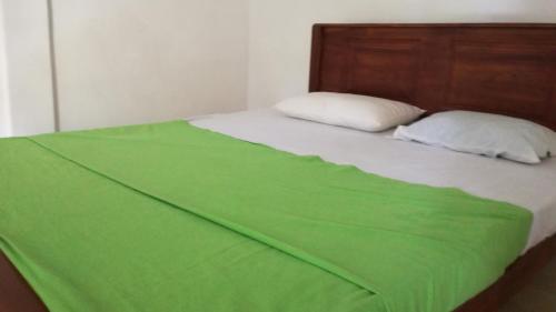 a green blanket laying on top of a bed at Sigiri Forest View in Sigiriya