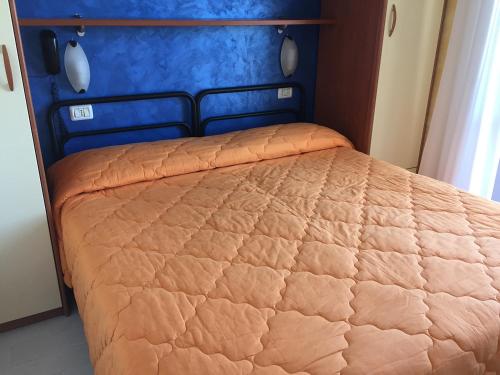 a bed with an orange comforter in a room at Hotel Viking in Rimini