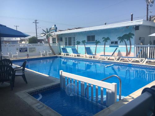a swimming pool with chairs and a building at Surf Haven Motel in North Wildwood