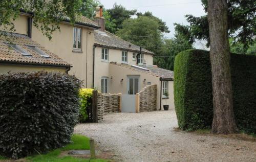 a house with a hedge in front of a driveway at Pippin Heath House B&B in Holt