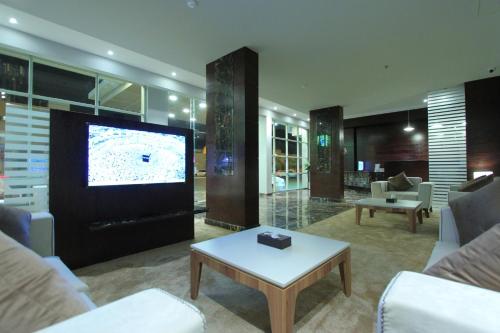 een woonkamer met een tv en een bank en een tafel bij Qasr Rayana Aparthotel in Buraydah