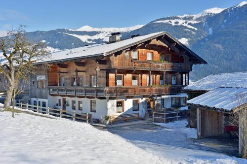 a large wooden house in the snow with mountains at Wermenerhof in Fügenberg