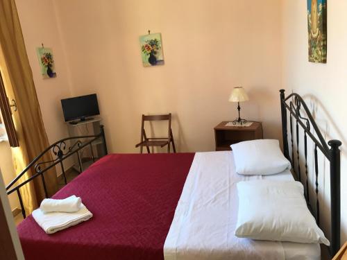 um quarto com uma cama grande com lençóis vermelhos e almofadas brancas em B&B Porticella em Marsala
