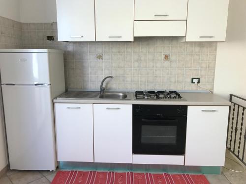 a kitchen with white cabinets and a sink and a refrigerator at B&B Porticella in Marsala