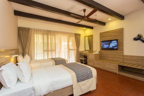 a bedroom with two beds and a flat screen tv at Jagatpur Lodge by Annapurna in Khargauli