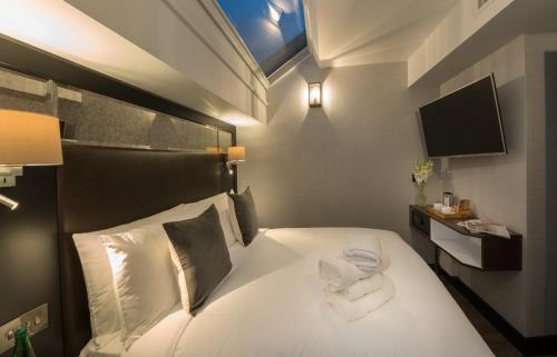 a bedroom with a bed with white sheets and a television at Camden Enterprise Hotel in London