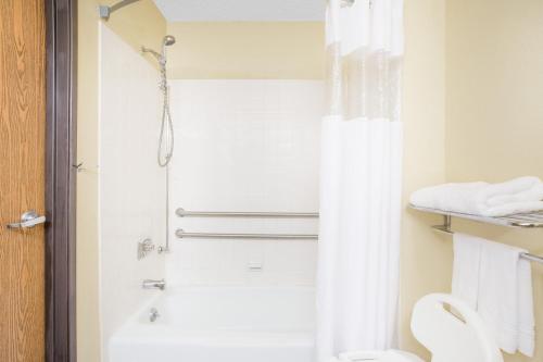 a bathroom with a shower and a white toilet at Super 8 by Wyndham Roanoke VA in Roanoke