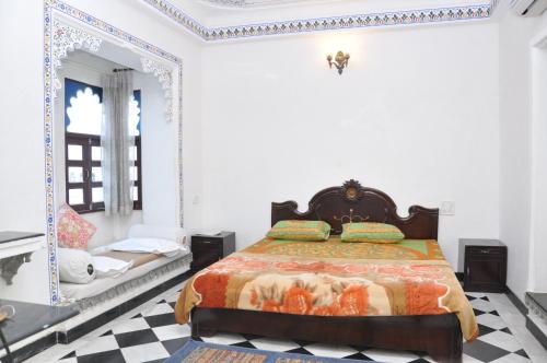 a bedroom with a bed and a mirror at Hotel Gangaur Palace in Udaipur