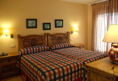 a bedroom with a bed and a desk and a lamp at Hotel Garabatos in Navarredonda de Gredos