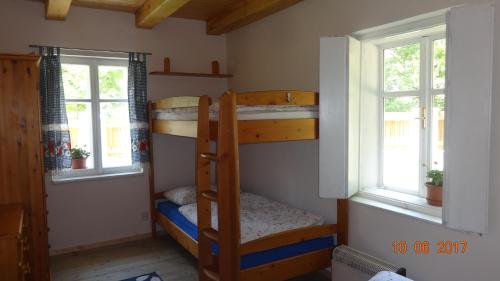 two bunk beds in a room with two windows at Chaloupka za potůčkem in Županovice