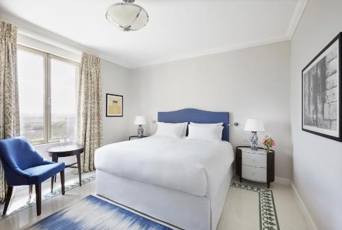 a bedroom with a white bed and a blue chair at The Phoenicia Malta - The Leading Hotels of the World in Valletta