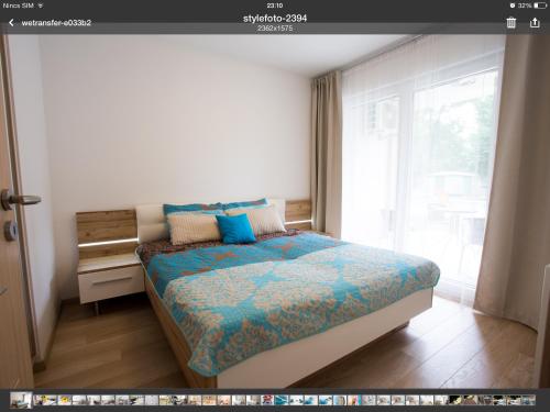 ザマールディにあるStylish Apartment Zamárdiのベッドルーム1室(青い掛け布団、窓付)