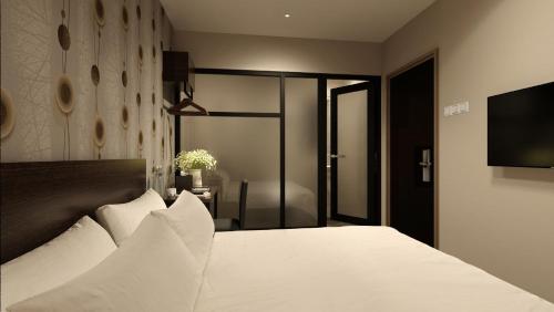 a bedroom with a white bed and a flat screen tv at The Square Hotel in Skudai