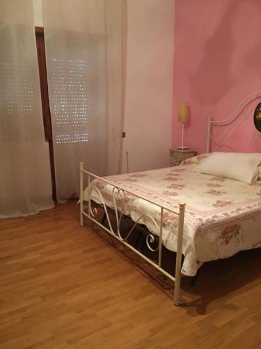 a bedroom with a bed with a pink wall at La Maison Blanche in Borghesiana 