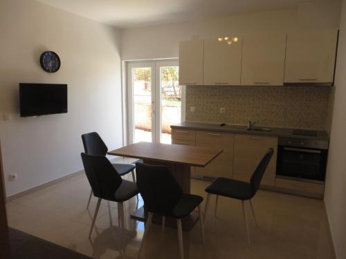 a kitchen with a wooden table and black chairs at Luka Apartments in Biograd na Moru