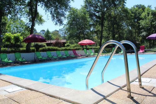 une piscine avec chaises et parasols dans l'établissement Les Chalets du Gélat, nature et calme, à Noaillan