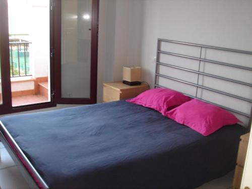 a bedroom with a large bed with pink pillows at Apartamento MPS Jardines de Nuevo Vera in Vera