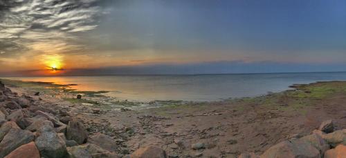 a sunset over a beach with rocks and the ocean at Chalet 44 in Grand Barachois
