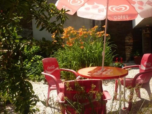 a table and chairs with an umbrella in a garden at Pensión Santa Rosa in Samos