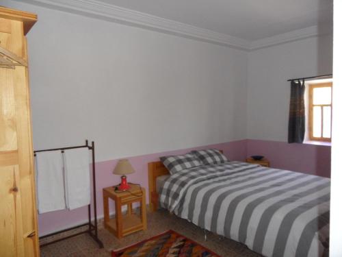a bedroom with a bed and a table with a lamp at Gite Tigmi Azrur in Tabant