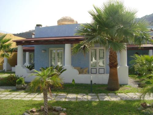 a blue house with palm trees in front of it at Hotel Bougainville in Lipari