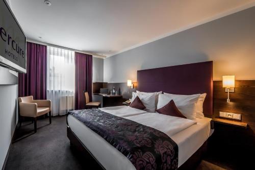 a hotel room with a large bed and a desk at Mercure Frankfurt City Messe in Frankfurt