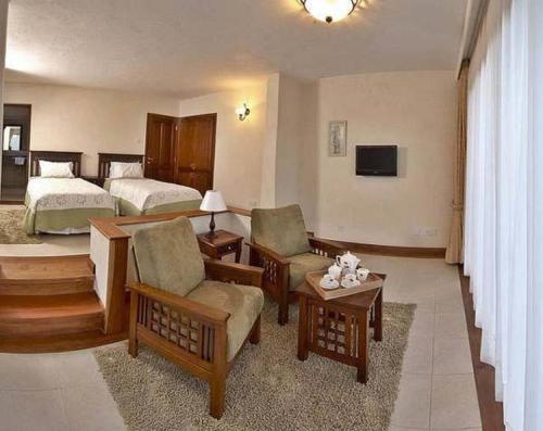 a hotel room with two beds and a living room at The Great Rift Valley Lodge & Golf Resort in Naivasha
