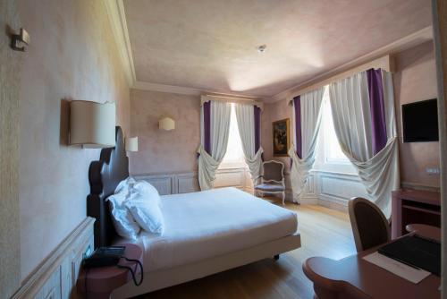 a hotel room with a bed and a desk and two windows at Villa Lattanzi in Marina Palmense