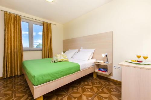 una camera da letto con un grande letto con una coperta verde di Apartments Glavan a Privlaka (Brevilacqua)