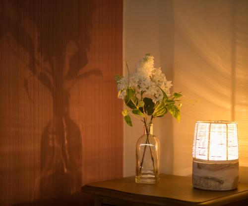 un jarrón con flores en una mesa junto a una vela en Willoughby Apartment, en Bath
