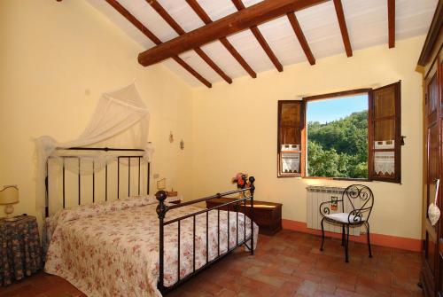 a bedroom with a bed and a window and a chair at Podere SantaAdele in Montepulciano