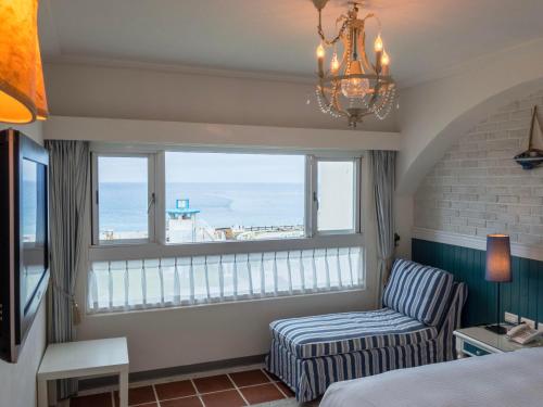 a bedroom with a window with a chair and a couch at Hotel Bayview in Dahan