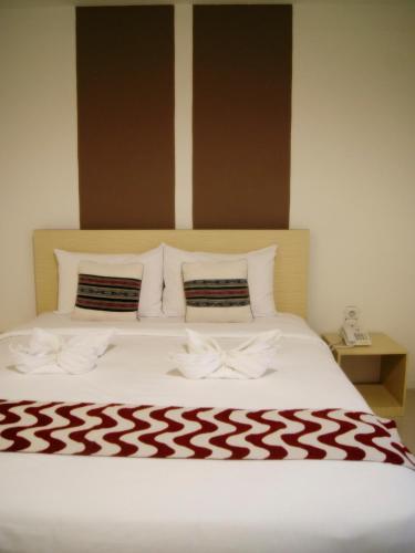 a white bed with a red and white blanket on it at LEOS Hotel in Tomohon