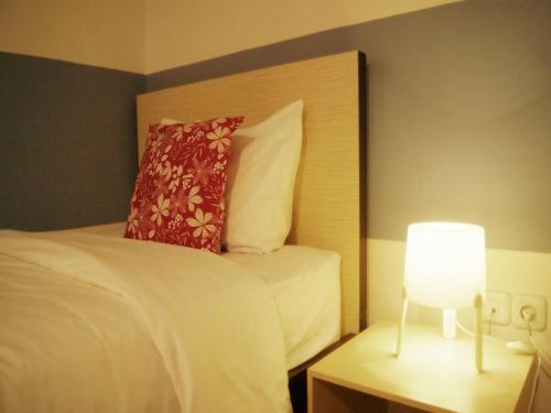 a bedroom with a bed with a pillow and a lamp at LEOS Hotel in Tomohon