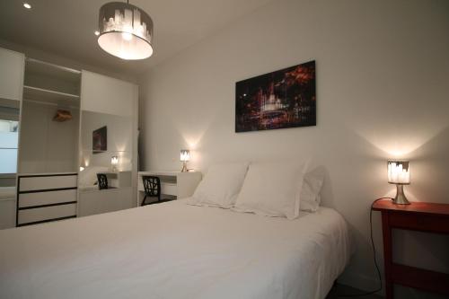 une chambre avec un grand lit blanc avec deux lampes dans l'établissement Cozy Select, à Paris