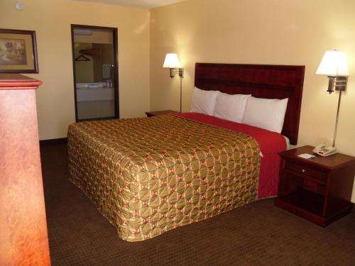 a hotel room with a bed with a red bedspread at Budget Inn Flagstaff in Flagstaff
