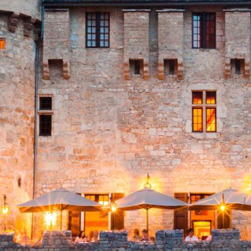 a building with tables and umbrellas in front of it at Château De La Caze Piscine & Spa - Ste Enimie in Sainte-Énimie