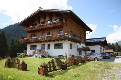 a large wooden house with a fence in front of it at Pension Sattelkopf in Sankt Anton am Arlberg