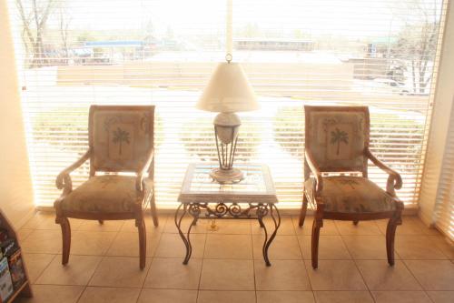 two chairs and a table with a lamp in a room at Highland Country Inn Flagstaff in Flagstaff