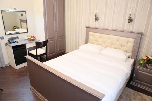 a bedroom with a large white bed with a desk at D'Rami in Almaty
