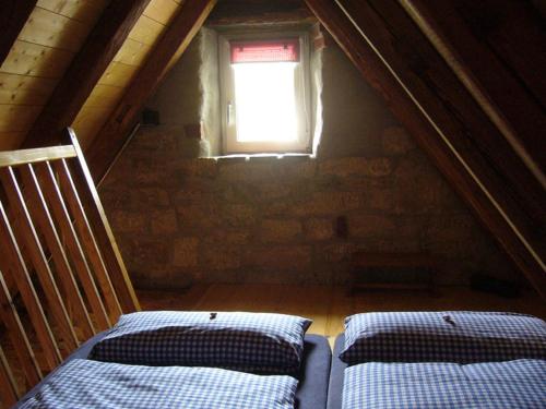 a attic room with two beds and a window at Ferienwohnungen Taubenschlag in Creglingen